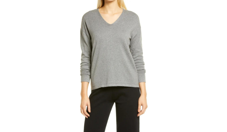 Blonde woman wearing gray v-neck sweater and black pants.