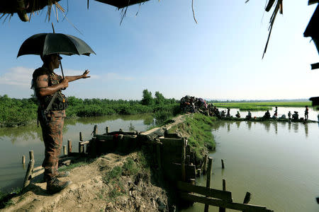 A Bangladeshi border guard stops Rohingya refugees who fled from Myanmar as they wait to be let through after crossing the border in Palang Khali, Bangladesh October 16, 2017. REUTERS/Zohra Bensemra