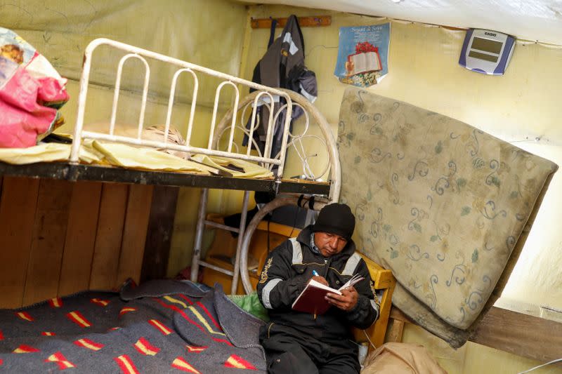 An artisanal gold miner writes in a notebook in his room in La Rinconada, in the Andes