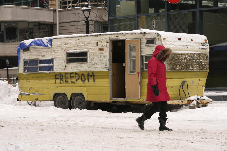 A resident of Ottawa walks past a camper trailer in downtown on Sunday, Feb. 20, 2022. A protest, which was first aimed at a COVID-19 vaccine mandate for cross-border truckers but also encompassed fury over the range of COVID-19 restrictions. (Adrian Wyld/The Canadian Press via AP)