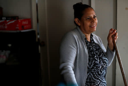 Sandra Gutierrez, who fled from gang violence in Honduras with her family and was granted asylum by the United States in 2016, stands as she pauses from sweeping the floor at her home in Oakland, California, U.S., May 30, 2017. Picture taken May 30, 2017. REUTERS/Stephen Lam