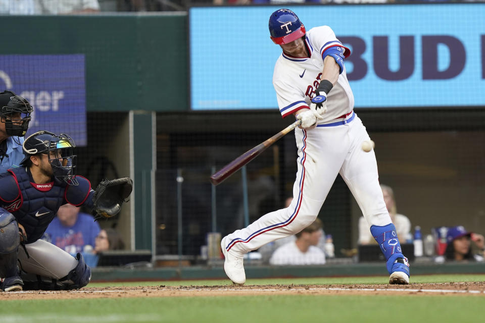 Texas Rangers Sam Huff swings for an RBI single in front of Atlanta Braves catcher Travis d'Arnaud during the second inning of a baseball game in Arlington, Texas, Saturday, April 30, 2022. Zach Reks scored on the play. (AP Photo/LM Otero)