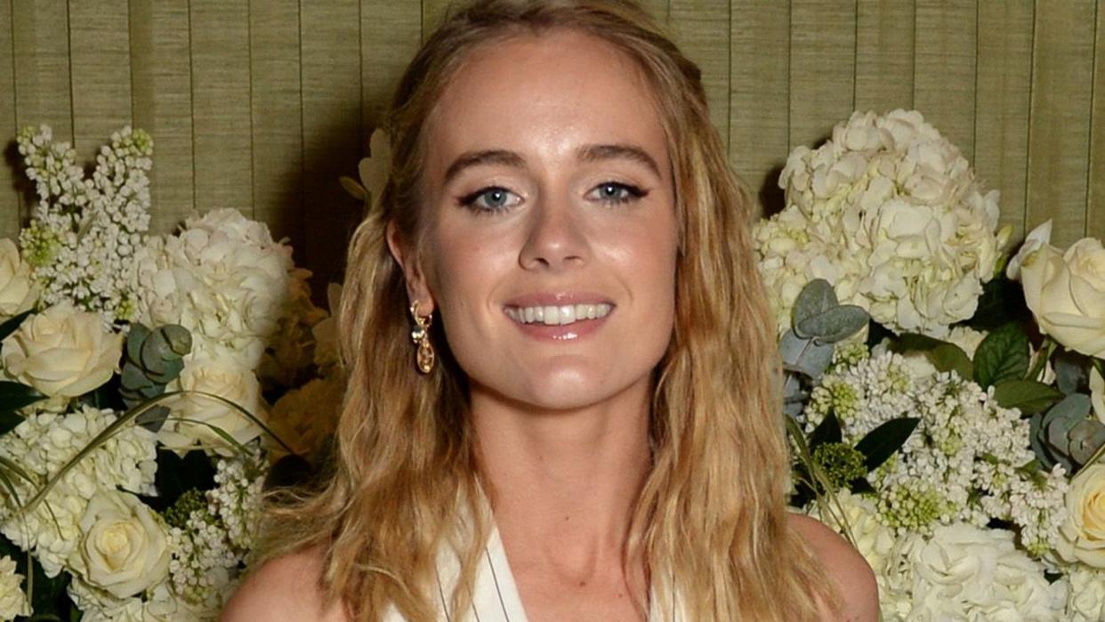 Cressida Bonas in a white suit in front of flowers