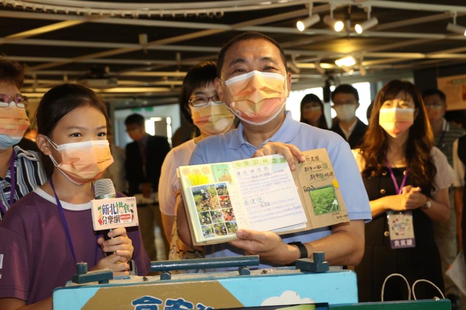 《圖說》侯友宜市長展示稻米小書內容，左為淡水區新市國小6年級學生林恩莉。〈社會局提供〉