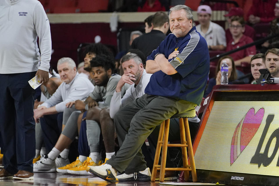 FILE - West Virginia head coach Bob Huggins, right, and Director of Basketball Operations Josh Eilert, center left, watch from the sidelines during the first half of an NCAA college basketball game against Oklahoma, March 1, 2022, in Norman, Okla. Eilert was named interim coach at West Virginia on Saturday, June 24, 2023, a week after Huggins resigned. (AP Photo/Sue Ogrocki, File)