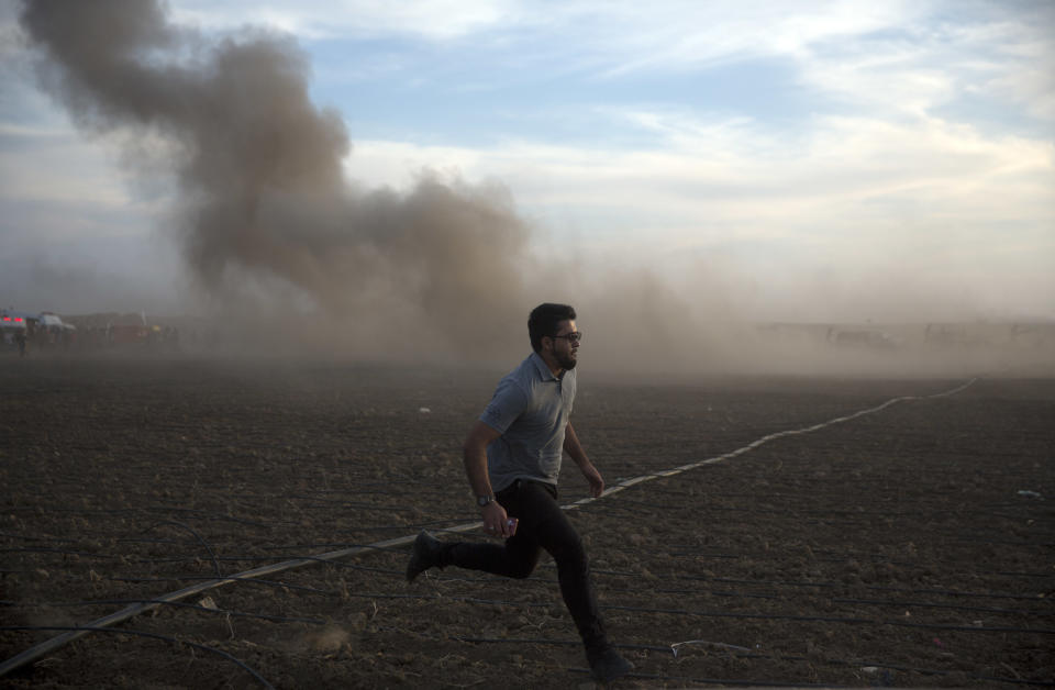 A Palestinian man runs for cover as smoke raises following an Israeli missile strike during a protest at the Gaza Strip's border with Israel, Friday, Oct. 5, 2018. (AP Photo/Khalil Hamra)