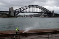 A worker cleans the mostly deserted waterfront area of the Sydney Opera House