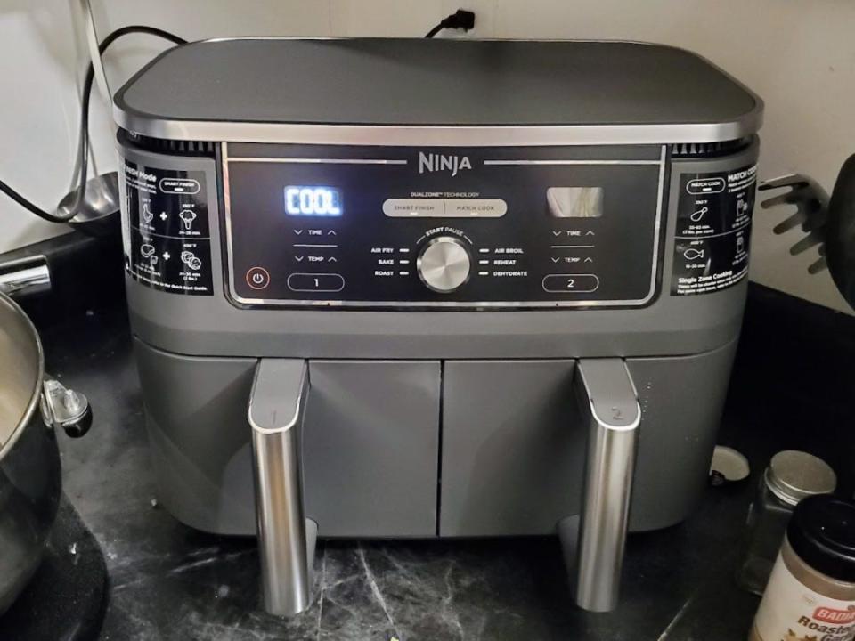 The Ninja DZ401 Foodi DualZone XL 2-Basket Air Fryer is displayed on a kitchen counter.