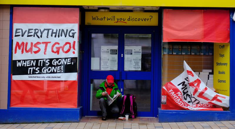 A man reads a newspaper as he sits in the door of a closed retail unit in Blackpool