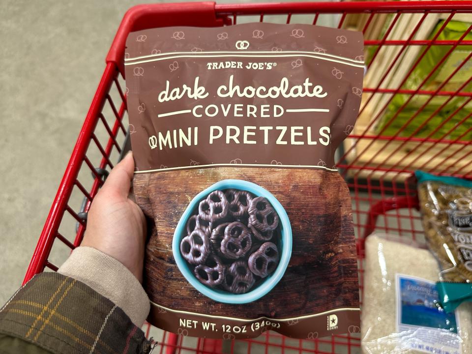 hand holding up a bag of trader joe's dark chocolate covered mini pretzels