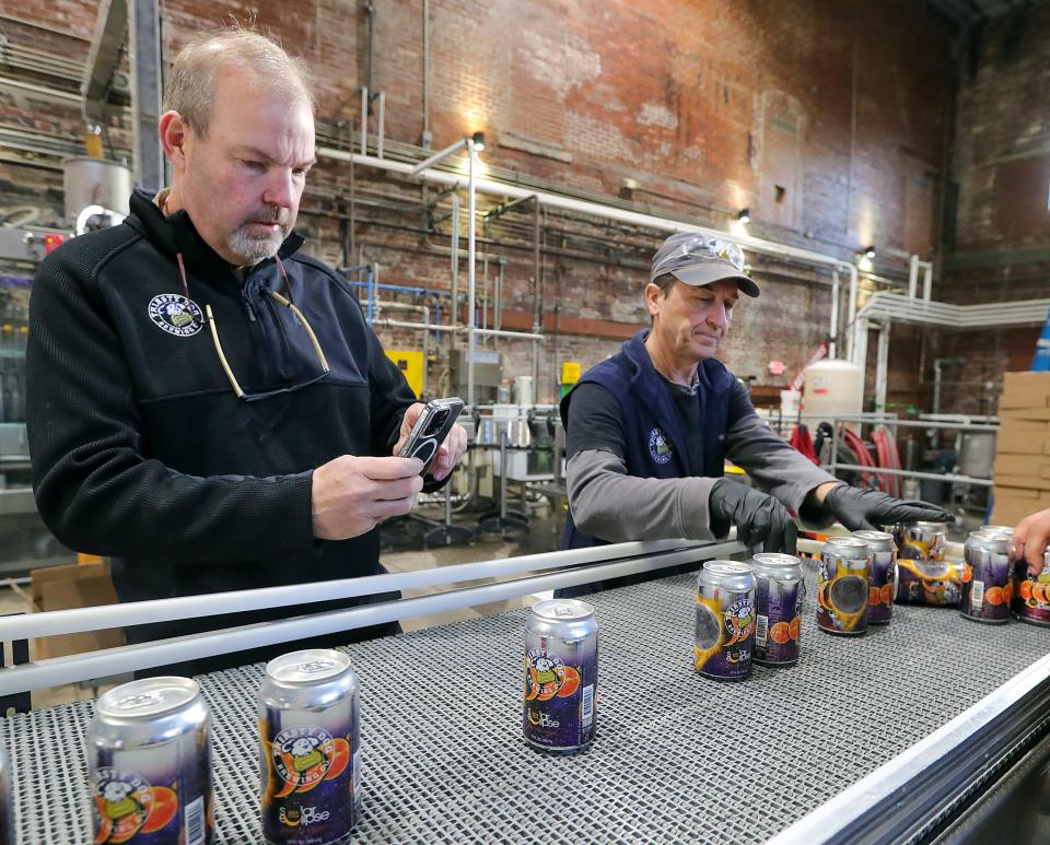 Thirsty Dog Brewing Company co-owner John Najeway takes cell phone video of the Solar Eclipse Vienna lager rolling off the canning line on March 21.