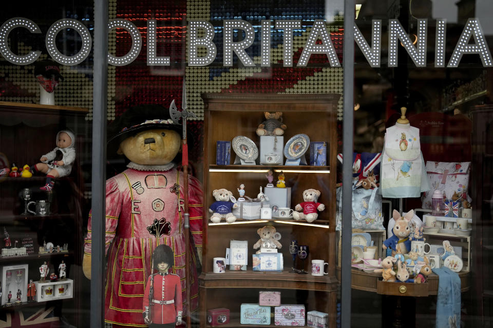 FILE - Souvenir items for Britain's Queen Elizabeth II's Platinum Jubilee are displayed for sale in the front window of the Cool Britannia store near Buckingham Palace, in London, Thursday, May 26, 2022. Britain is getting ready for a party featuring mounted troops, solemn prayers — and a pack of dancing mechanical corgis. The nation will celebrate Queen Elizabeth II’s 70 years on the throne this week with four days of pomp and pageantry in central London. (AP Photo/Matt Dunham, File)