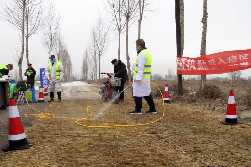 FILE PHOTO: Police officers and workers in protective suits are seen at a checkpoint on a road leading to a farm owned by Hebei Dawu Group where African swine fever was detected, in Xushui