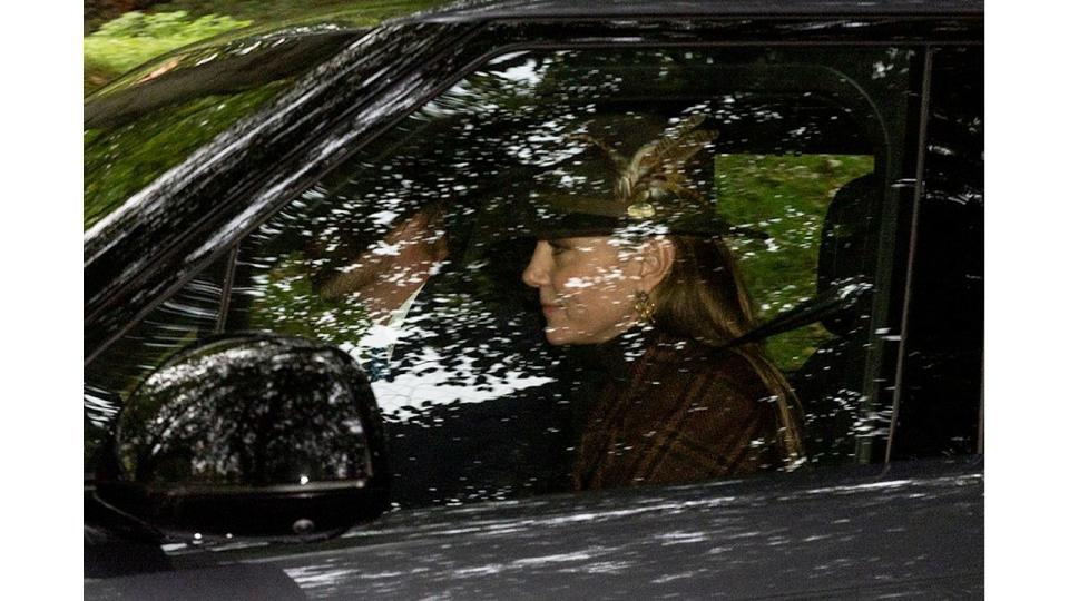 Kate Middleton in a brown checked coat and a feathered hat