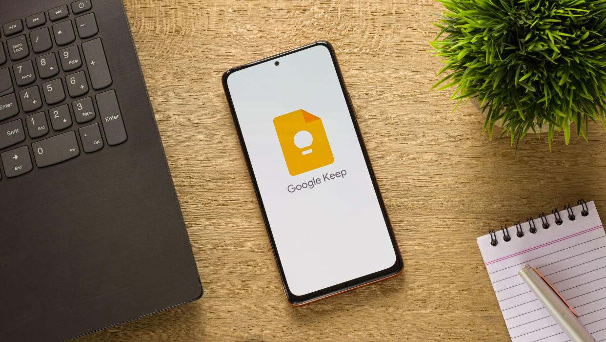  Google Keep icon displayed on a smartphone on a table next to a notepad. 