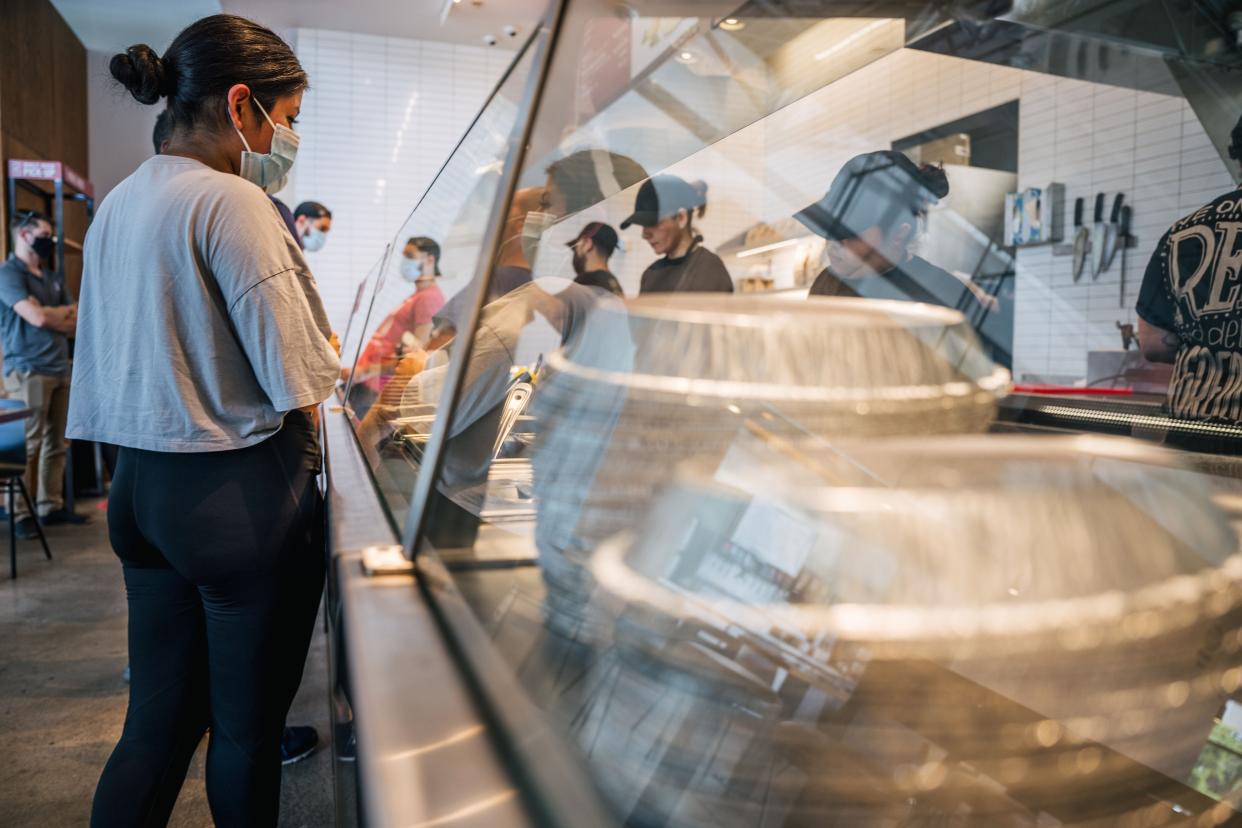 A woman waits in line for food at a Chipotle Mexican Grill.