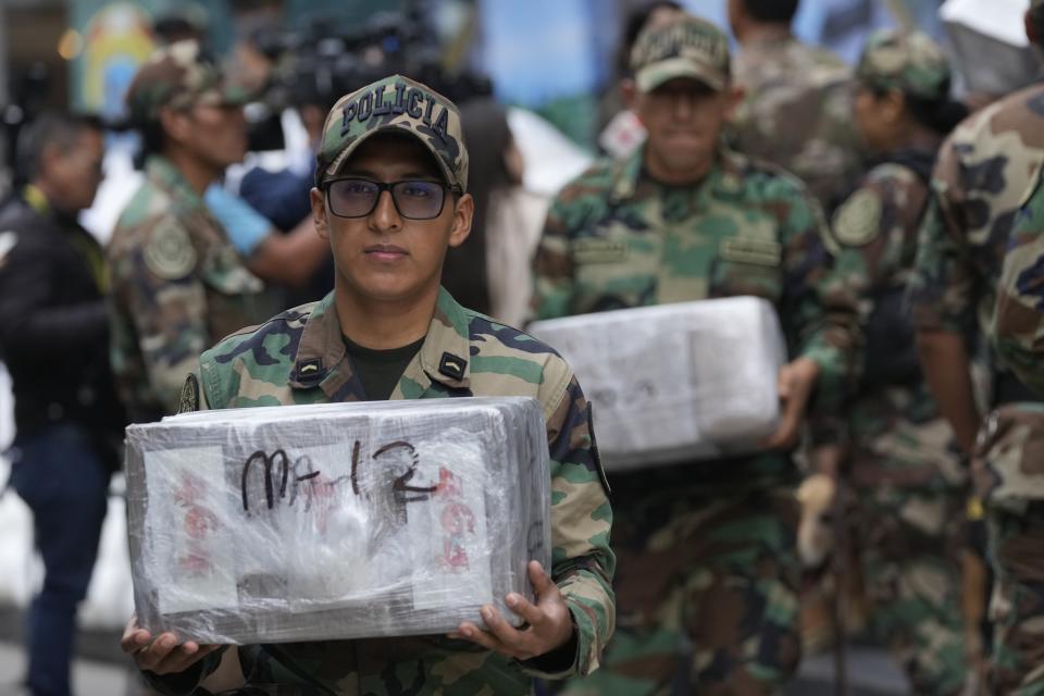 Agentes antinarcóticos transportan paquetes de cocaína incautada durante una presentación ante los medios en una base policial antinarcóticos en Lima, Perú, el lunes 6 de mayo de 2024. (AP Foto/Martín Mejía)