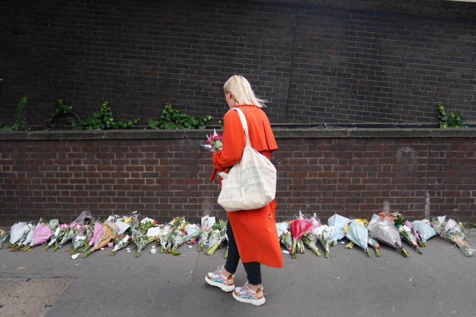 A woman lays flowers near the scene in Croydon (PA)