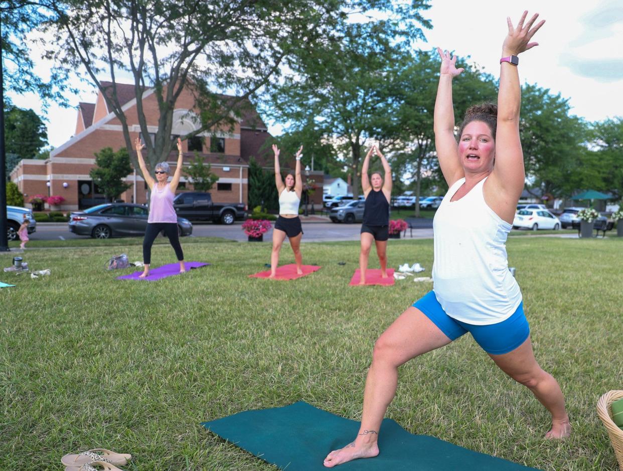 Amber Phillips, owner of Rise Yoga Ohio on Broadway, leads a yoga class at the Town Center park July 14. The city plans to build an enhanced performance venue to replace the temporary stage currently being used for performances and events at the park.