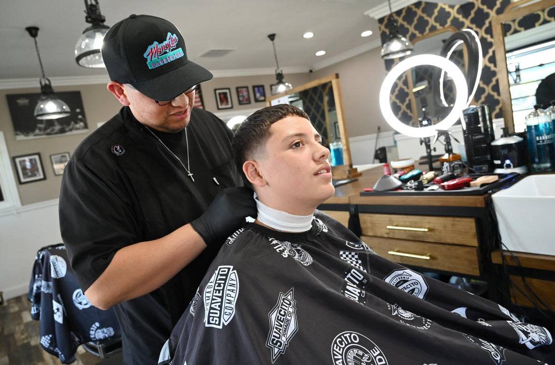 Levi Villasenor, right, prepares for a haircut from his dad Yuniel Villasenor, owner of Money Line Barbershop, who won the poll for best barbershop in the area Friday, Aug. 26, 2022 in Fresno.
