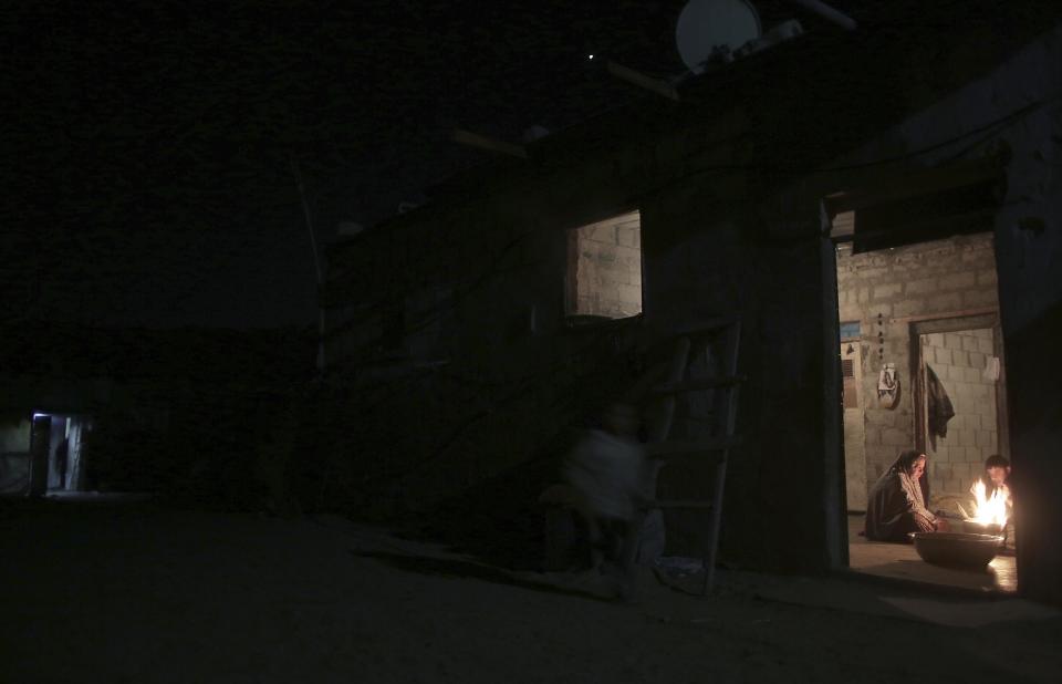 In this Sunday, Jan. 15, 2017 photo, a Palestinian family warm themselves up with a fire inside their makeshift house during the power cut in a poor neighborhood in town of Khan Younis in the southern Gaza Strip. At night, large swaths of the Gaza Strip plunge into darkness _ the result of chronic and worsening power outages. In crowded city streets, the only source of light comes from the headlights of passing cars. The power shortages are the worst to hit Gaza since Hamas seized control of the territory 10 years ago. (AP Photo/ Khalil Hamra)