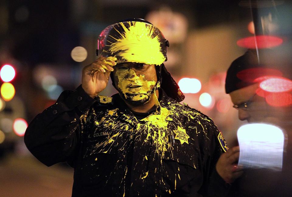 Un policía de la ciudad de Oakland se limpia de pintura lanzada por un grupo de manifestantes del movimiento Occupy Oakland, una sección del grupo Occupy Wall Street y que al igual que en otras ciudades se unieron a distintos grupos de protesta durante el año 2012. (Photo by Justin Sullivan/Getty Images)