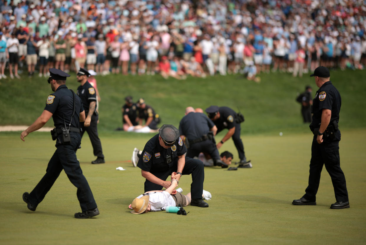 A group of protesters stormed the 18th green on Sunday afternoon and let off smoke before Tom Kim forced a playoff with Scottie Scheffler in Connecticut.