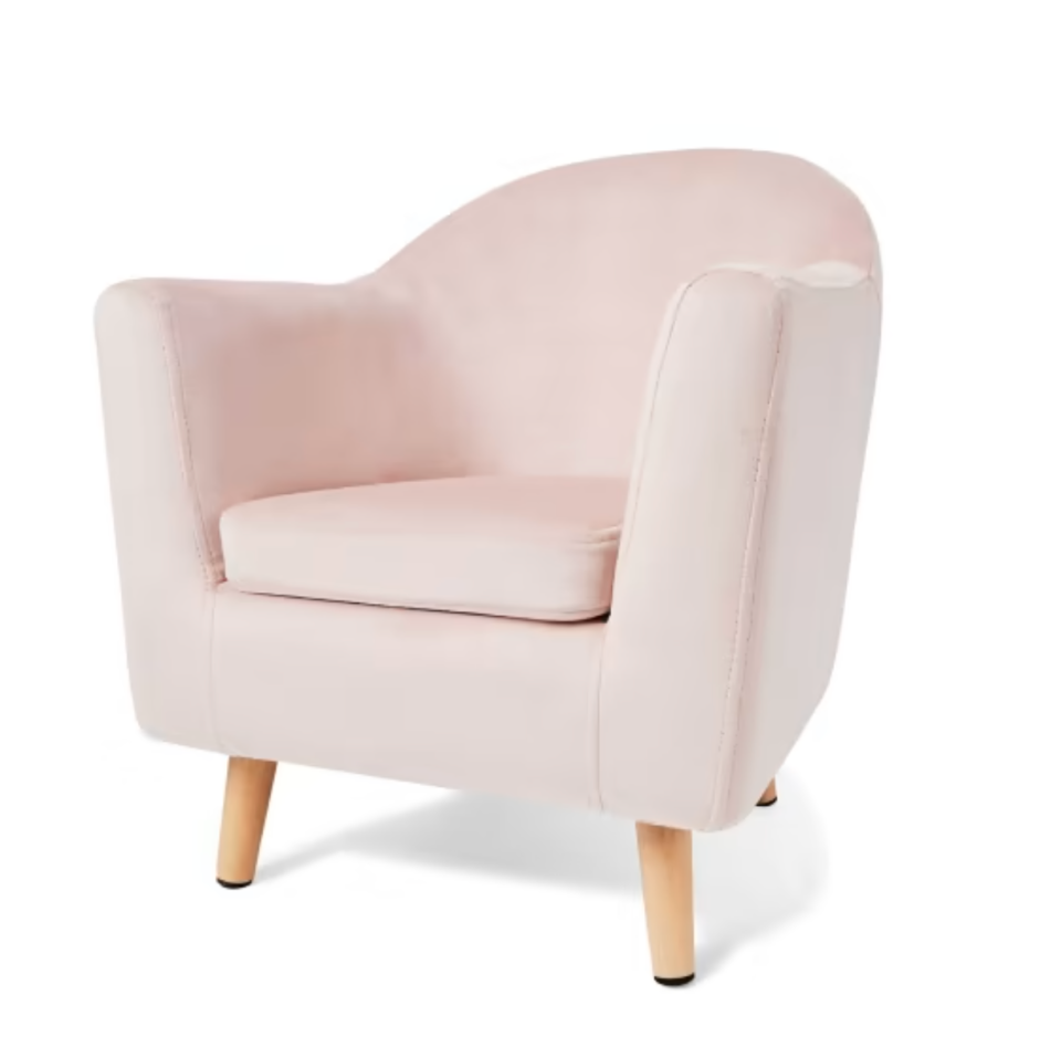 Pink kids' velvet armchair with timber legs sits on a white background