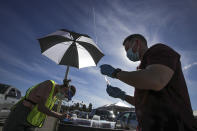 Dr. Richard Dang, right, Assistant professor USC School of Pharmacy prepares a COVID-19 vaccine as mass-vaccination of healthcare workers starts at Dodger Stadium on Friday, Jan. 15, 2021, in Los Angeles. (Irfan Khan/Los Angeles Times via AP, Pool)