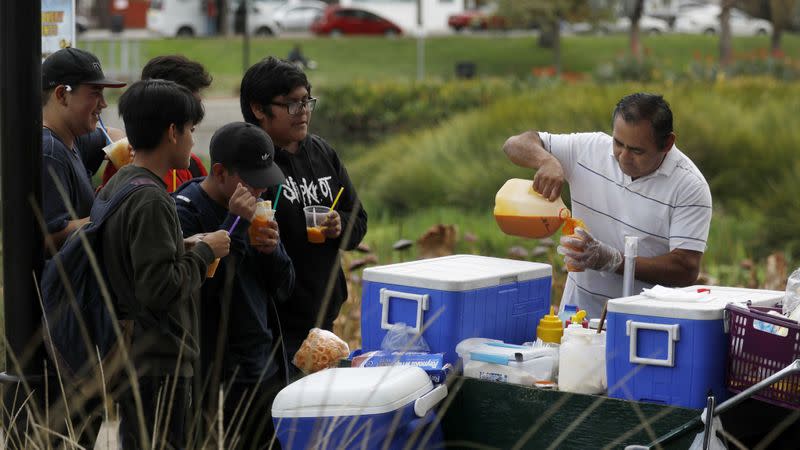 Street vendor Neftali Lopez serves customers from his food cart in Echo Park in Los Angeles in this undated story. The Huntington Beach City Council approved a permanent permit process for sidewalk vendors, with strict limits. (Credit: Francine Orr / Los Angeles Times)