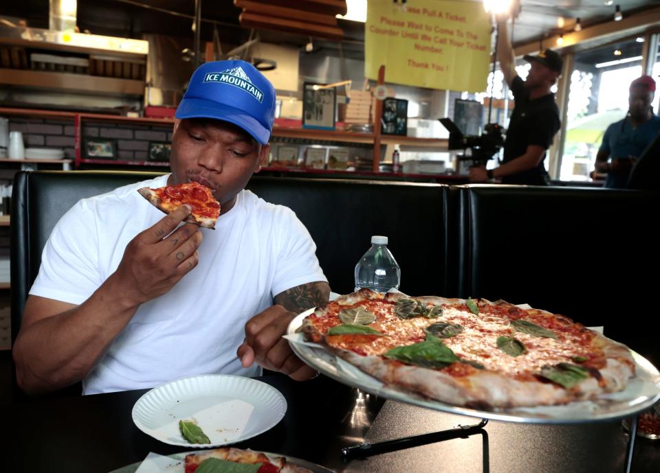New Lions running back David Montgomery tries out a slice of pizza at Fredi's The PizzaMan in Melvindale on Friday, June 16, 2023.