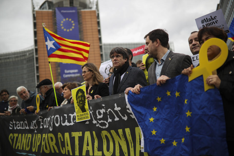 Catalonia's former regional president Carles Puigdemont, fourth right, hold a banner with others during a protest in front of the European Commission headquarters in Brussels, Tuesday Oct. 15, 2019. New disruptions to Catalonia's transportation network on Tuesday followed a night of clashes between activists and police over the conviction of separatist leaders, as Spanish authorities announced an investigation into the group organizing the protests. (AP Photo/Francisco Seco)