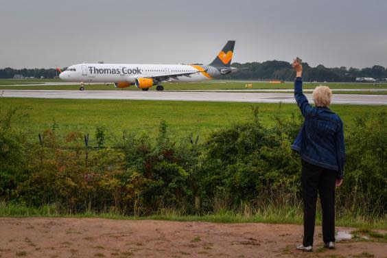 A woman waves as a Thomas Cook aircraft departs from Terminal 1 at Manchester Airport (Getty)