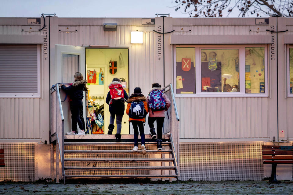 Pupils go to a school which is partially located in containers in Frankfurt, Germany, Monday, Dec. 14, 2020. Germany goes into a lockdown on Wednesday, Dec. 16, 2020. (AP Photo/Michael Probst)