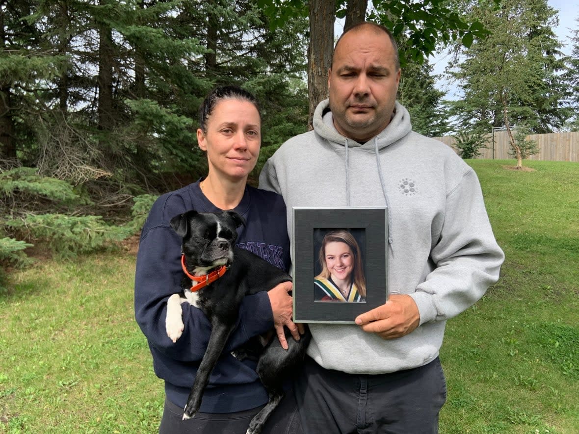 Michelle Kwasnycia and Byran Kwasnycia hold a graduation photo of their daughter Jade Kwasnycia, who died in a vehicle collision at the intersection of Highway 16A and Range Road 20, 16 kilometres northwest of Spruce Grove, in August 2022.   (Gabriela Panza-Beltrandi/CBC - image credit)