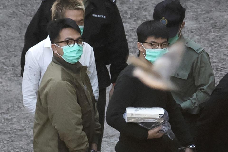 Hong Kong activists Joshua Wong, right, and Ivan Lam, left, are escorted by correctional services officers to a prison van.