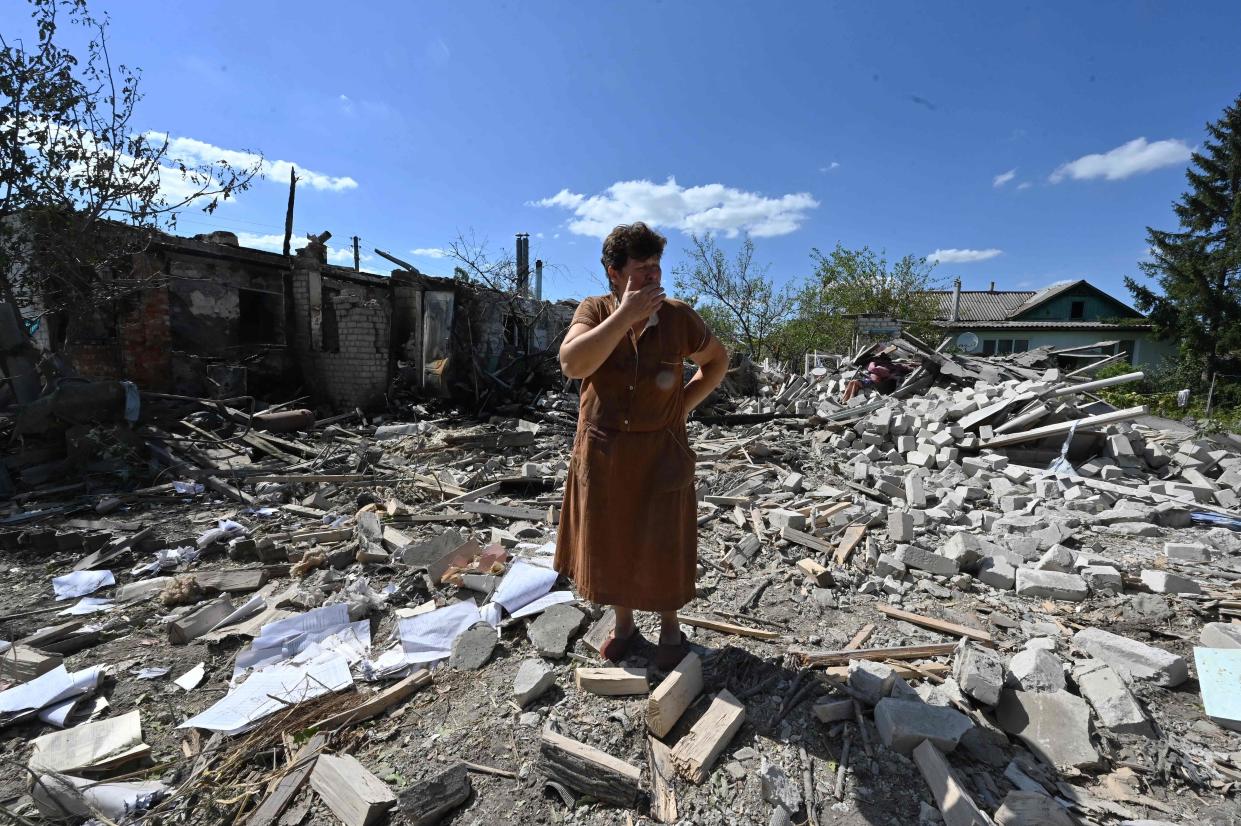 Tatyana Skrypnikova, 60, who sustained light shrapnel wounds, stands among debris of the house of her neighbours destroyed following a shelling in the village ofnZaoskillya, near Kupiansk, Kharkiv Oblast (AFP via Getty Images)