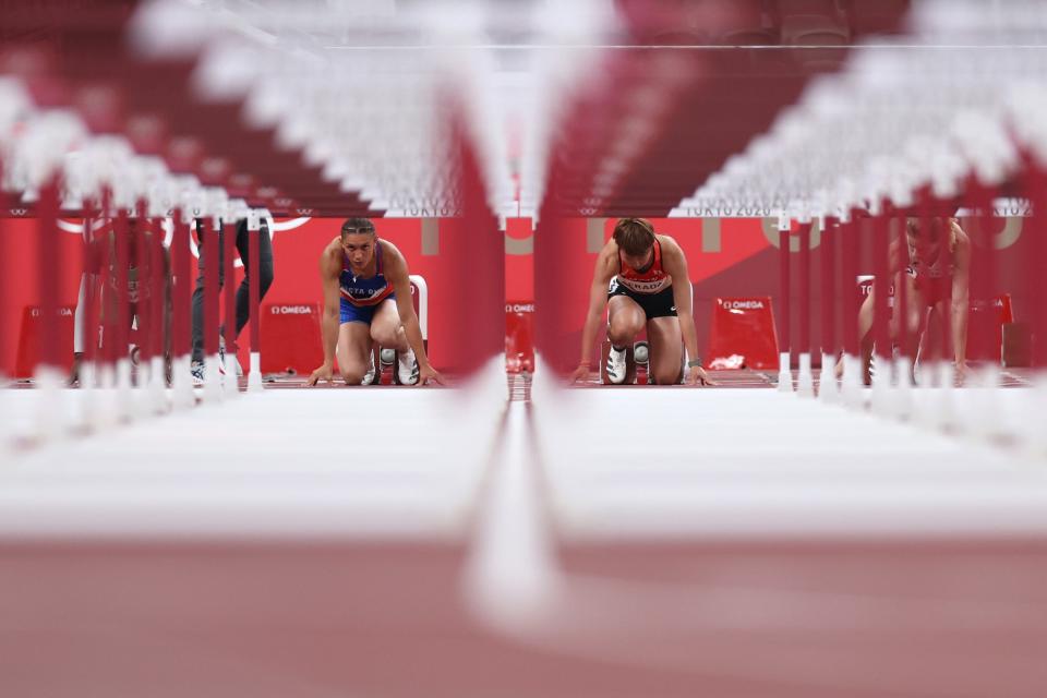 Two athletes prepare to compete in the 100m hurdles at the Tokyo Olympics.