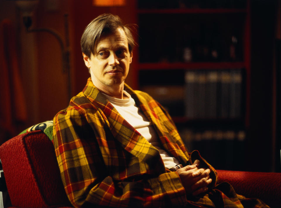 Buscemi sitting on a couch in a bland robe in ghost world