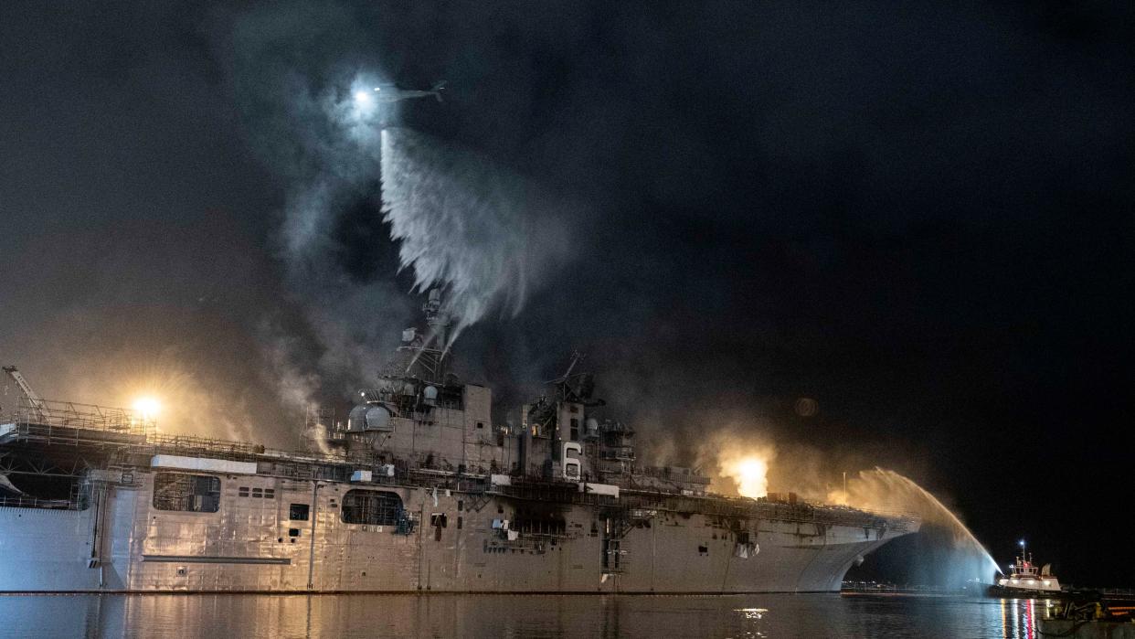 A helicopter from Helicopter Sea Combat Squadron (HSC) 3 combats a fire aboard the amphibious assault ship USS Bonhomme Richard (LHD 6) at Naval Base San Diego, Tuesday, July 14, 2020.