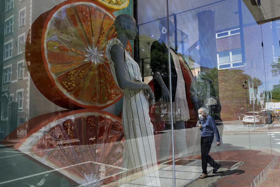 A passer-by, wearing a mask out of concern for the coronavirus, walks past a storefront window, Tuesday, June 16, 2020, in Cambridge, Mass. According to the Commerce Department U.S. retail sales jumped by a record 17.7% from April to May, with spending partially rebounding after the coronavirus had shut down businesses, flattened the economy and paralyzed consumers during the previous two months. (AP Photo/Steven Senne)