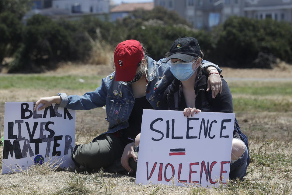 Sam Rippola, left, puts her arm around Isabelle Murphy as they observe a moment of silence before marching at a protest calling for an end to racial injustice and accountability for police in San Francisco, Sunday, June 21, 2020. (AP Photo/Jeff Chiu)