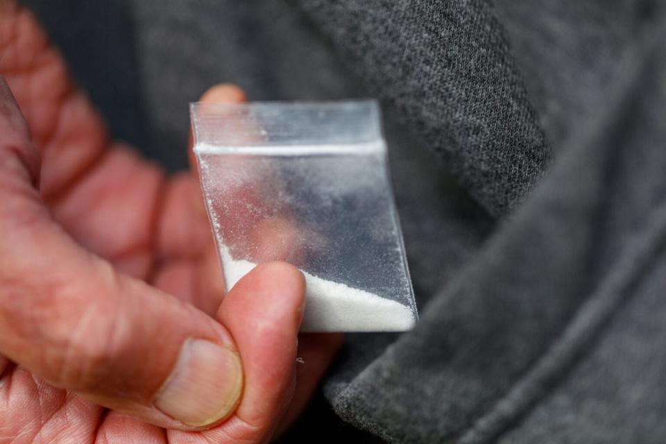 A man holds a baggie of fentanyl.