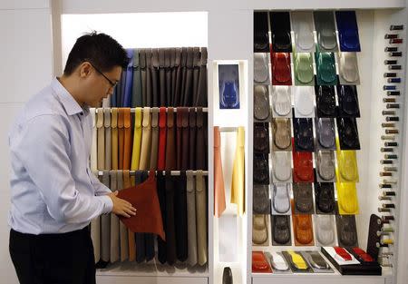 Sales Manager Raymond Liu talks about the varieties of customisation for upholstery and paint colours that customers can choose from for their vehicles, at an Aston Martin showroom in Singapore August 1, 2014. REUTERS/Edgar Su