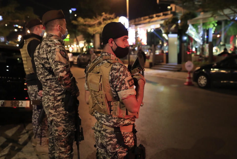 Lebanese security forces wearing protective masks to prevent the spread of coronavirus, as they stand guard at a street full of restaurants where revelers celebrating the New Year Eve, in Beirut, Lebanon, early Friday, Jan. 1, 2021. Lebanon ended the year with more than 3,500 newly registered infections of coronavirus and 12 new deaths as its health minister rang appealed to Lebanese to take precautions while celebrating to avoid what he called wasting sacrifices made in combatting the virus. (AP Photo/Hussein Malla)