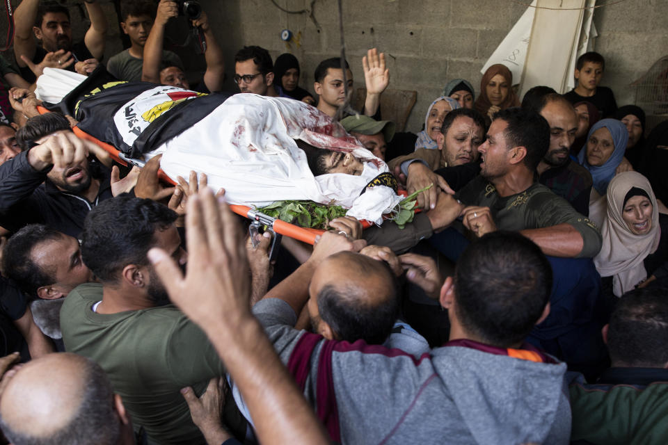 Mourners carry the body of Islamic Jihad militant, Abdullah Al-Belbesi, 26, who was killed in Israeli airstrikes, out of the family home during his funeral, in the town of Beit Lahiya, Northern Gaza Strip, Wednesday, Nov. 13, 2019. Gaza's Health Ministry said Wednesday that more Palestinians have been killed by ongoing Israeli airstrikes, bringing the death toll in the escalation over the past two days to at least 18. (AP Photo/Khalil Hamra)