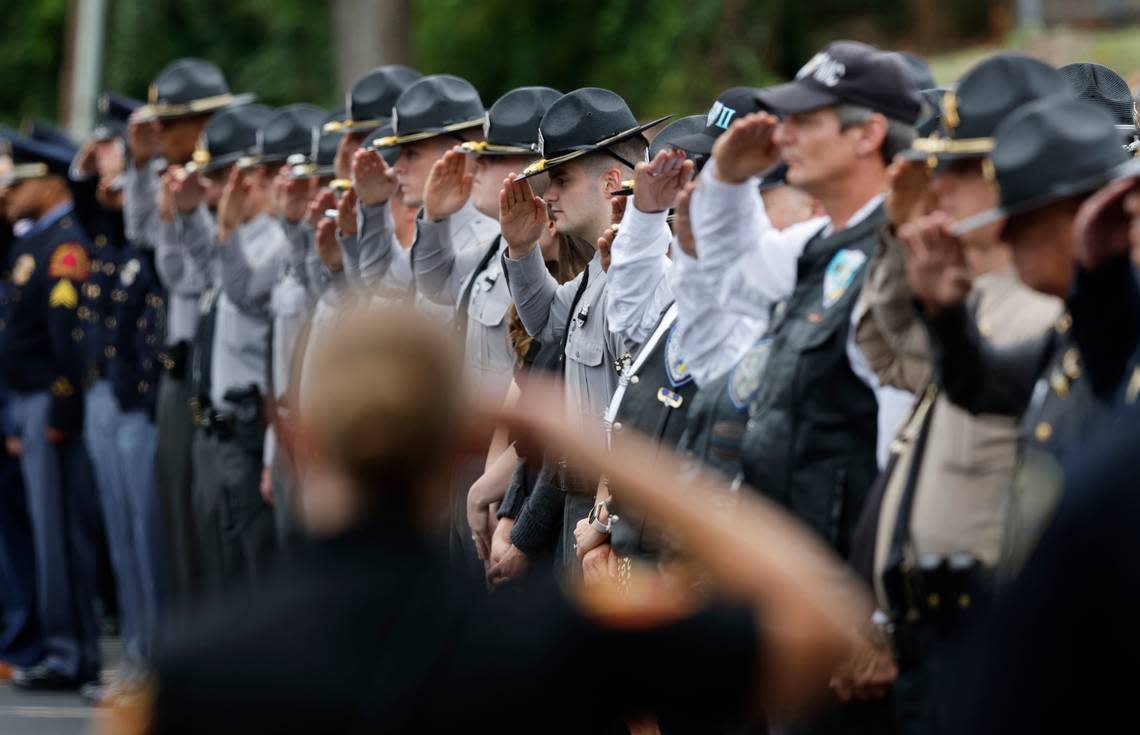 Officers salute after the N.C. State Highway Patrols Caisson Unit carrying slain Wake County Sheriffs Deputy Ned Byrd passed then during a procession for Deputy Byrd before his funeral at Providence Baptist Church in Raleigh, N.C., Friday, August 19, 2022.