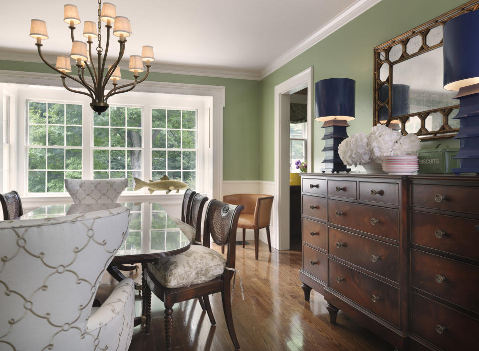 The Kravet upholstered wing chairs, the multiple arm chandelier and the blue painted pagoda lamps on the breakfront add a touch of whimsy and unexpected color in the space.