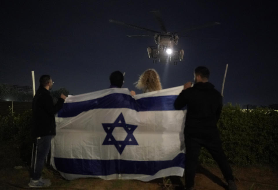 CAPTION CORRECTION CORRECTS LOCATION: People holding an Israeli flag watch the arrival of a helicopter transporting Israeli hostages released by Hamas at the Sheba Medical Center in Ramat Gan, Israel, Tuesday Nov. 28, 2023. Hamas and Israel released more hostages and prisoners under terms of a fragile cease-fire that held for a fifth day Tuesday. (AP Photo/Leo Correa)