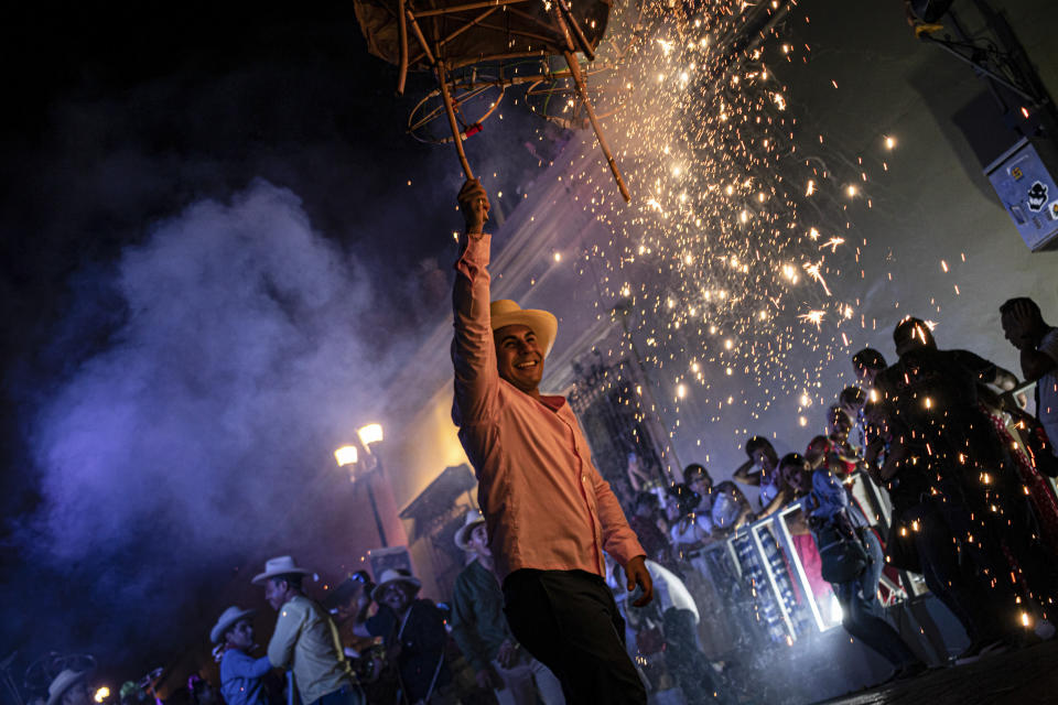 La gente desfila con fuegos artificiales durante el festival de la Guelaguetza en Oaxaca, México, el sábado 15 de julio de 2023. En el el evento promovido por el gobierno, 16 etnias indígenas y la comunidad afromexicana reivindican sus tradiciones a través de bailes, desfiles y venta de artesanías. (AP Foto/María Alférez)